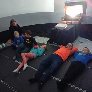 Uczniowie I i II klasy leżą w kapsule kina sferycznego
